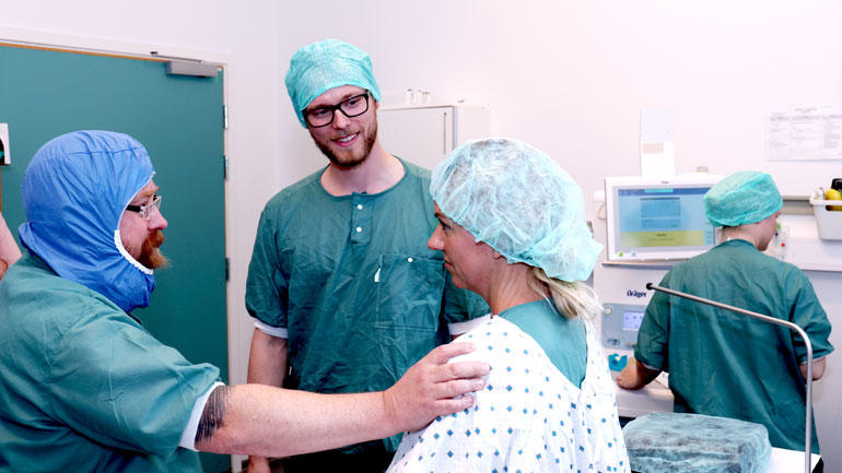 Operasjonssykepleiestudentene Bjørn Erik og Aleksander i praksis på operasjonsstua hvor de beroliger en kvinnelig pasient. 