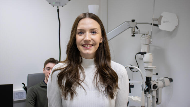 Karoline smiler foran optikerutstyr